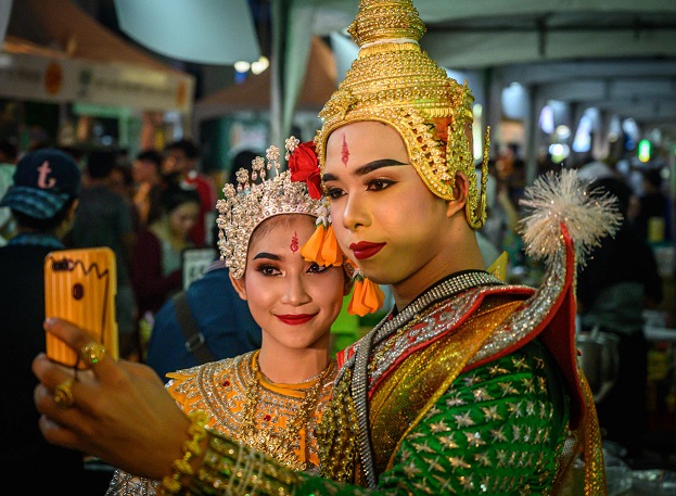 Traditional Thai dancers take a selfie picture before their performance at a street festival in Bangkok on December 15, 2019. (Photo by Mladen ANTONOV / AFP)