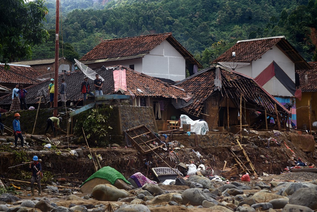 Sejumlah warga beraktivitas di dekat puing reruntuhan rumah yang rusak terkena banjir bandang di Kampung Cinyiru, Banjar Irigasi, Lebak, Banten. (Foto: ANTARA/Asep Fathulrahman)