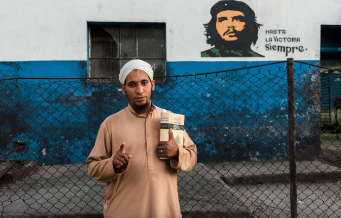 Seorang muslim Kuba berpose di depan tembok dengan gambar Che Guevara. Foto: Parallelozero
