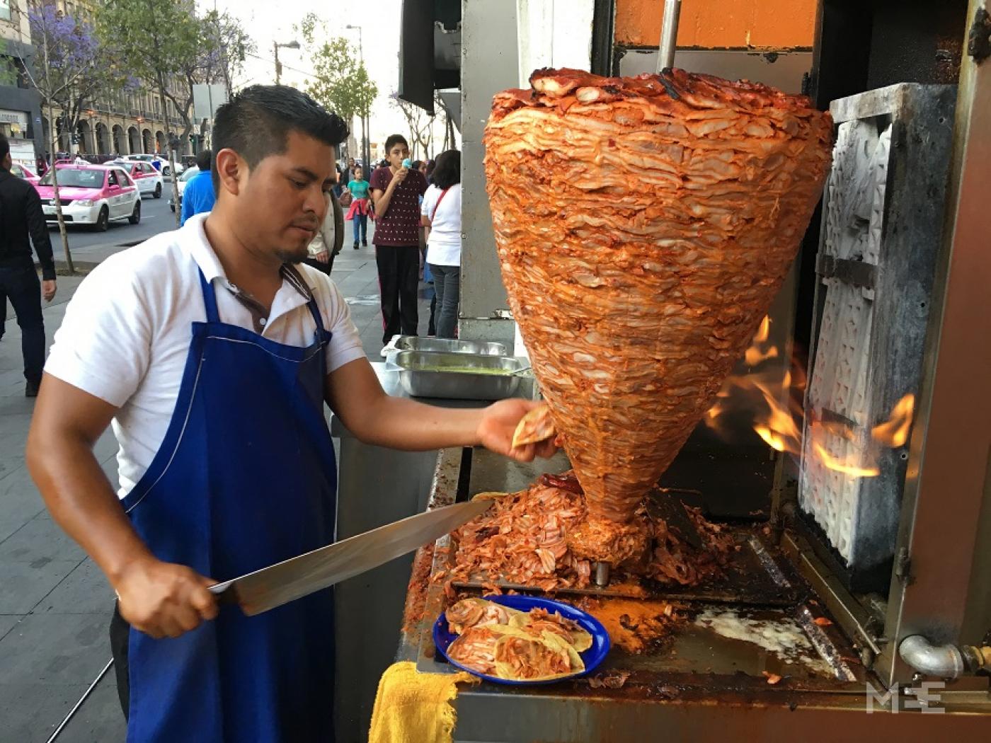 Seorang pedagang di Mexico City memotong daging untuk taco al pastor, hidangan yang diyakini berasal dari shawarma kebab, diperkenalkan oleh imigran Lebanon pada awal abad ke-20 (MEE/Alex Shams)