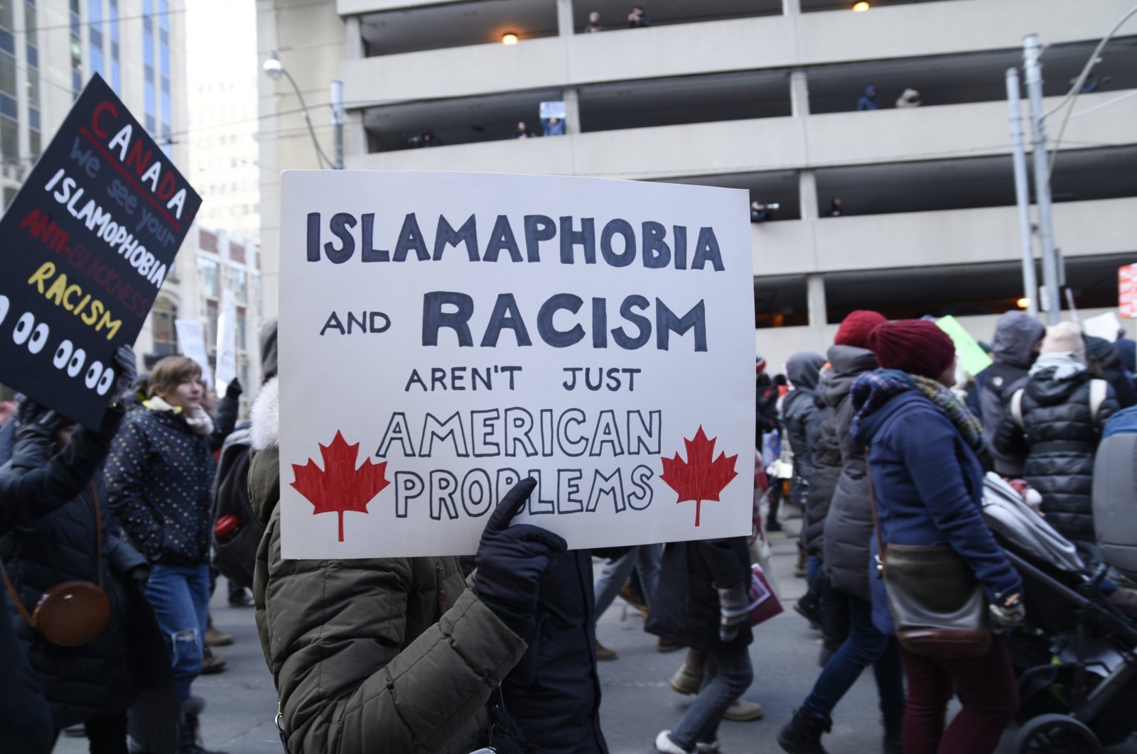 Orang-orang dengan poster yang menolak rasisme dan Islamofobia saat unjuk rasa di Toronto, Kanada, 4 Februari 2017. (Foto AP)