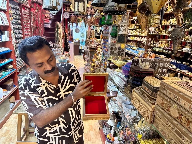 Razzaq menunjukkan kotak kayu berukir untuk dijual di salah satu toko tempat dia bekerja [Urooba Jamal/Al Jazeera]