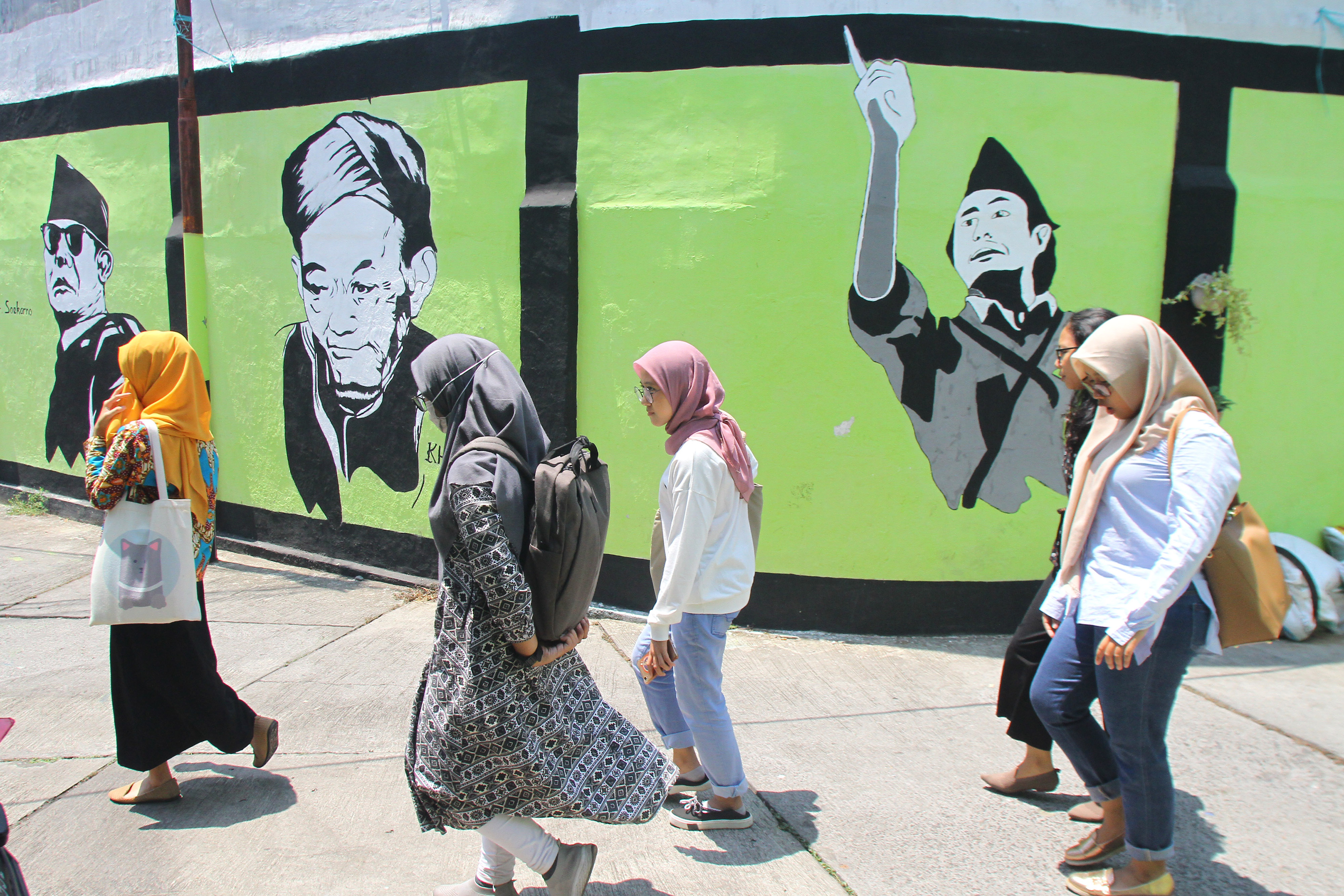 Pejalan kaki melintas di depan mural pahlawan nasional di Jalan Veteran Dalam, Malang, Jawa Timur, Kamis (7/11/2019). Warga setempat sengaja melukis mural di dinding tersebut untuk menghilangkan kesan kumuh sekaligus menanamkan rasa patriotisme pada masya