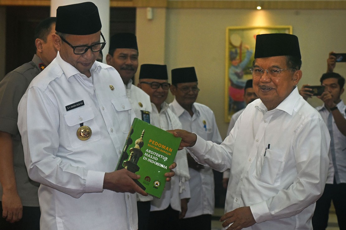 Ketua Umum DMI Jusuf Kalla menyerahkan buku Pedoman Arsitektur Masjid kepada Gubernur Banten Wahidin Halim usai pelantikan PW DMI Banten di Serang. 